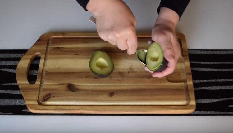 Žličicom odvojite meso avokada od kore.