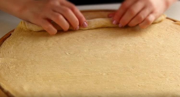 Nous transformons soigneusement les trois couches de pâte collées ensemble en un rouleau serré.