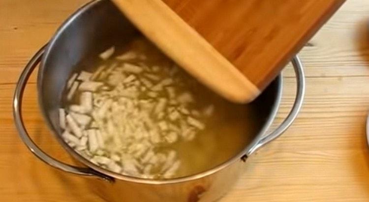 Mettez les pommes de terre et les oignons hachés dans le bouillon.