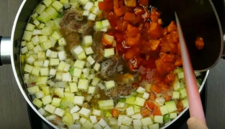 Cortar las papas, el calabacín en cubos, ponerlos en el caldo, agregar guisantes, carne y asar.