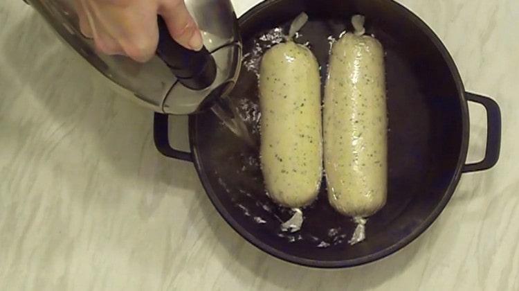 Nous mettons des saucisses avec soufflé dans la casserole. remplir avec de l'eau.