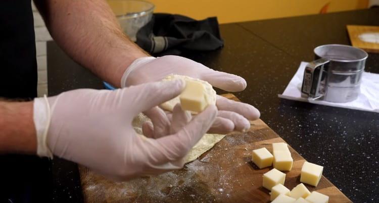 Dans chaque morceau de pâte, nous mettons un cube de fromage.