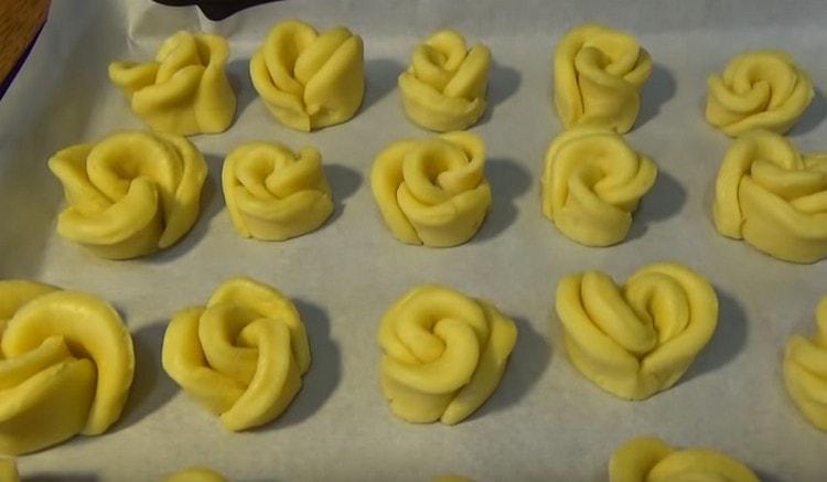 Les roses formées sont placées sur une plaque à pâtisserie recouverte de papier sulfurisé.