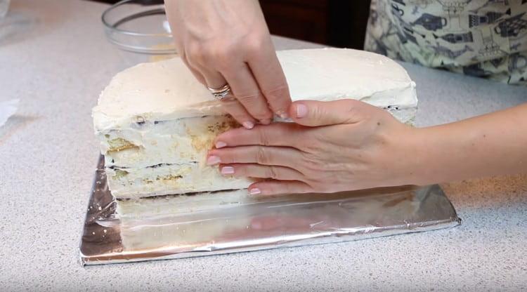Having greased the sides of the cake with the remaining cream, sprinkle them with biscuit crumbs.