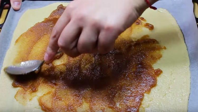 Transférer la pâte sur du papier sulfurisé sur une plaque à pâtisserie et graisser à la confiture.