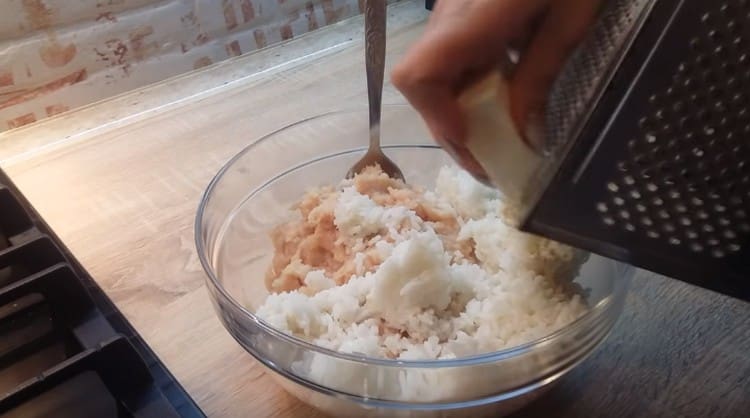 Le poulet émincé est combiné avec des oignons, du riz et du fromage fondu râpé.