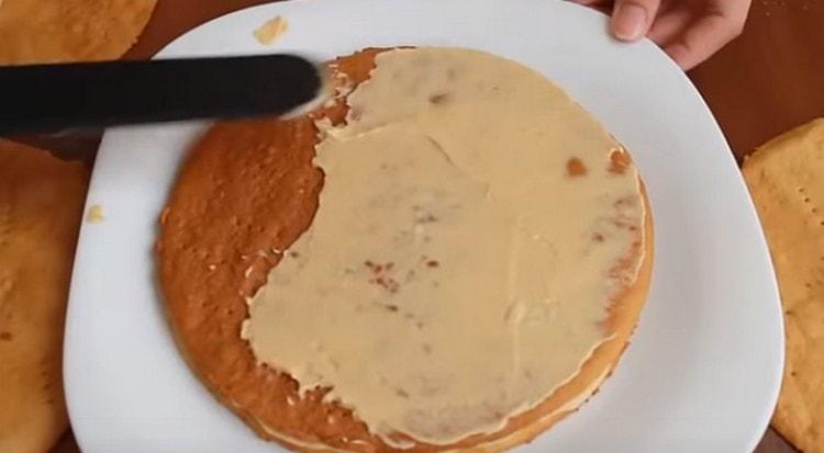 Engrasa los pasteles con crema, doblándolos uno encima del otro y formando un pastel.