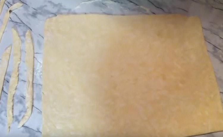 We take out the dough from the refrigerator and roll it into a rectangular layer to the size of the baking sheet.