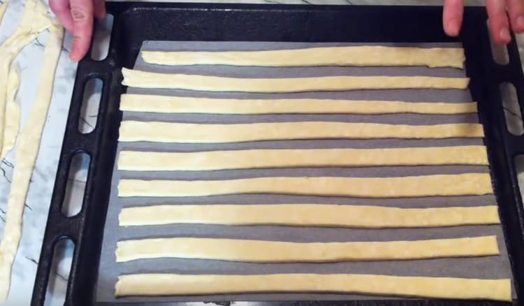 Nous étalons des bandes de pâte sur une plaque à pâtisserie recouverte de papier sulfurisé.