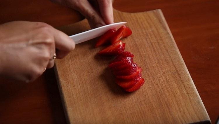 Pour décorer le dessert, coupez les fraises.