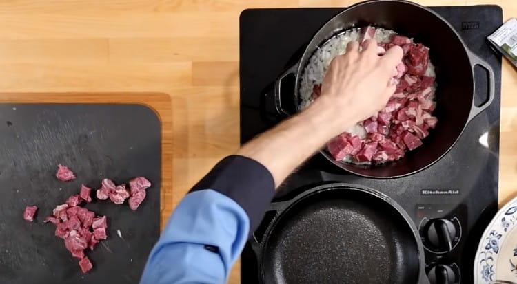 Couper la viande en petits morceaux et ajouter l'oignon au chaudron.