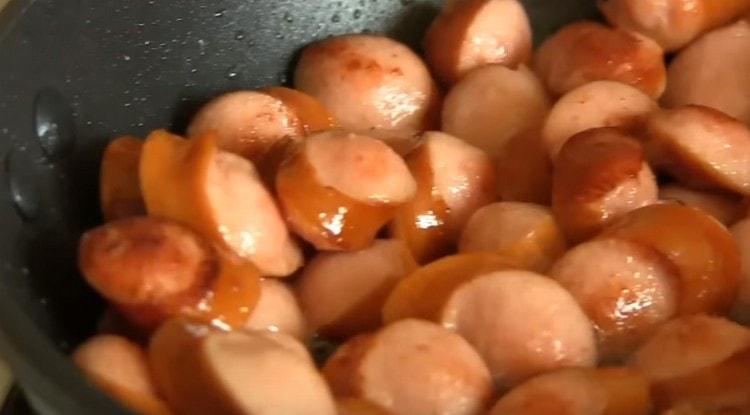 Dans une autre casserole, faire sauter les saucisses jusqu'à ce qu'elles soient dorées.