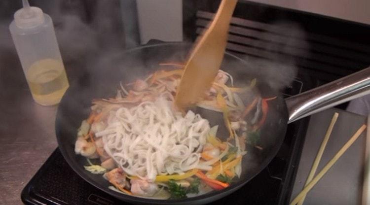 Nous répandons les nouilles dans la casserole pour le poulet et les légumes, mélanger.