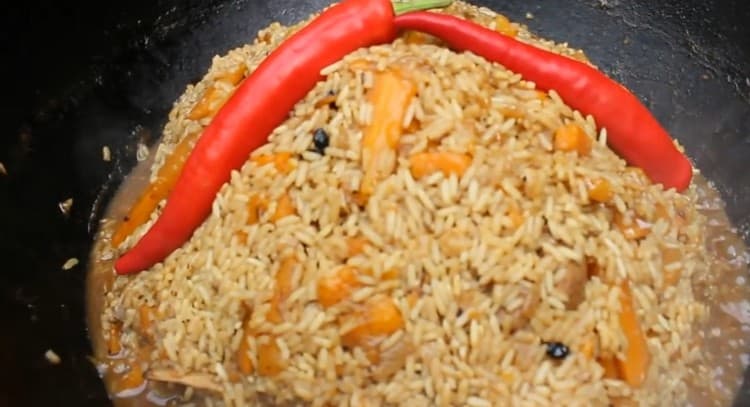 Almost at the end of cooking, we collect the pilaf in a slide, add pods of hot pepper to it.