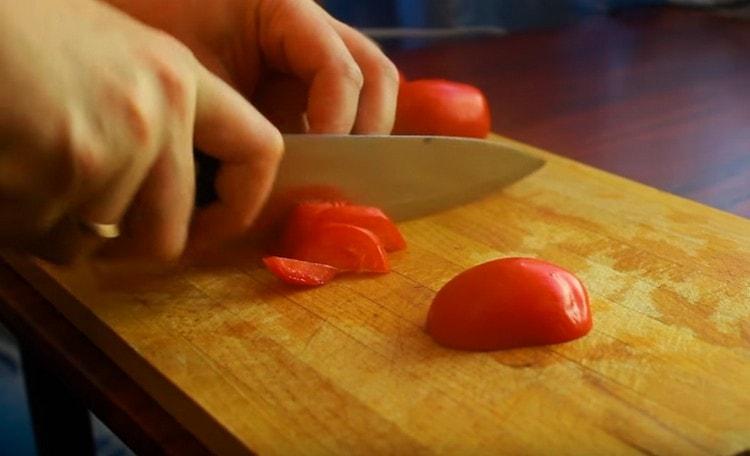 Nous coupons les tomates en fines demi-cercles.