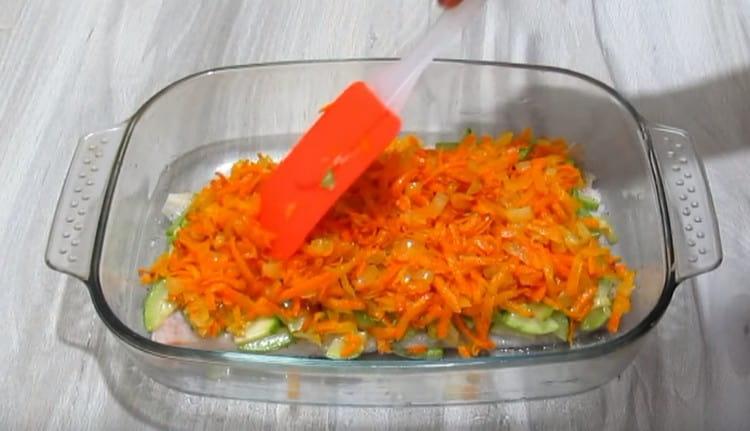 On top of the fish fillet we spread the zucchini layer, and on it already carrots with onions.