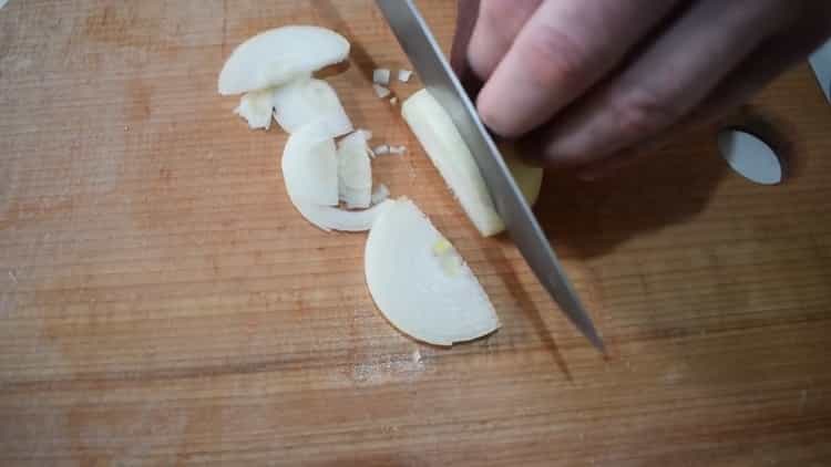 Para cocinar estofado de ternera con verduras, picar la cebolla