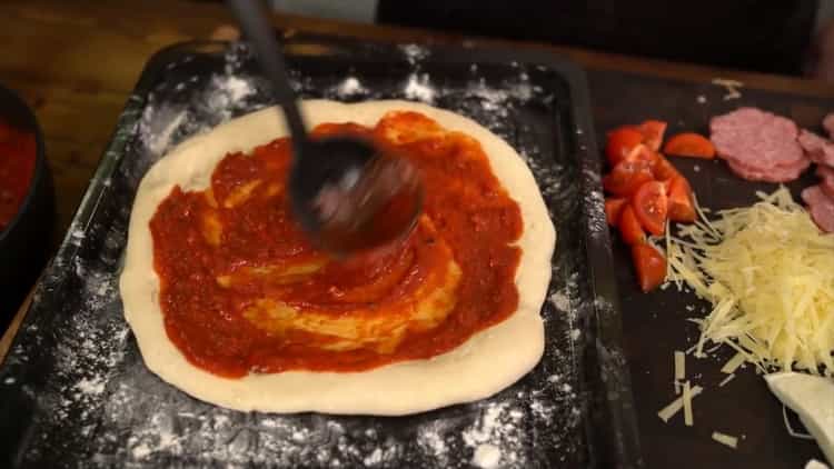 To make a classic pizza, grease the dough with sauce