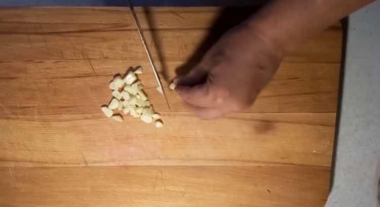 Upang magluto ng isang kuneho sa kulay-gatas sa oven, i-chop ang bawang