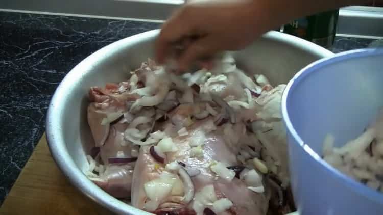 Para cocinar la marinada de conejo en el horno, mezcla la carne con la cebolla.