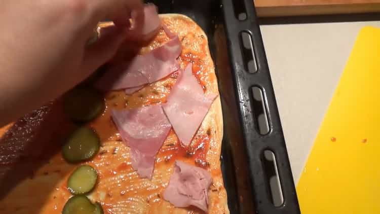 Para preparar los ingredientes para la pizza, ponga el jamón sobre la masa.