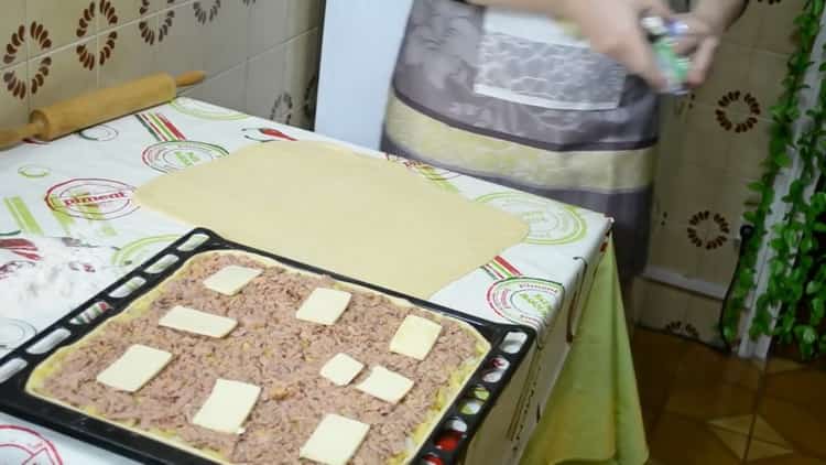 Pour préparer une tarte avec du poisson et des pommes de terre, mettez le beurre sur la garniture