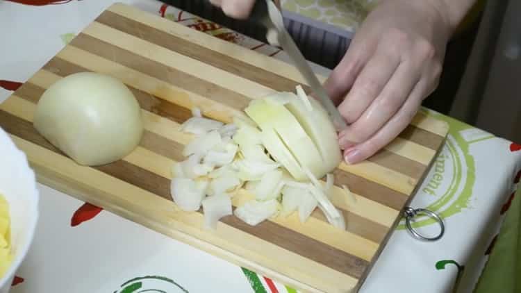 Pour faire une tarte avec du poisson et des pommes de terre, hachez l'oignon