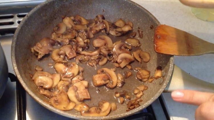 Freír los champiñones para hacer un pastel de pollo.