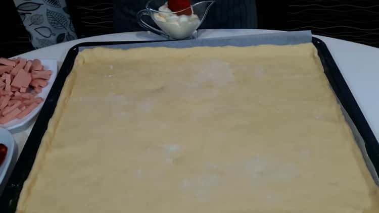 Pour faire une pizza à la maison, placez la pâte sur une plaque à pâtisserie