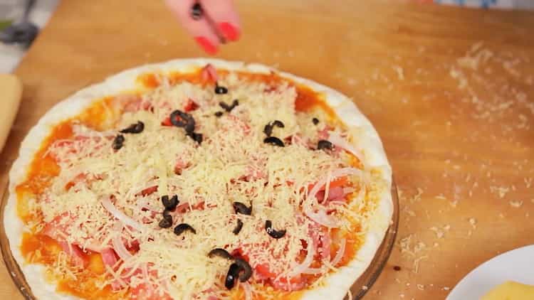 Da biste napravili pizzu u mikrovalnoj, na tortu stavite naribani sir