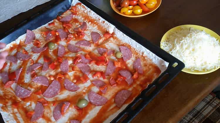 To cook pizza from pita bread in the oven, cut the sausage