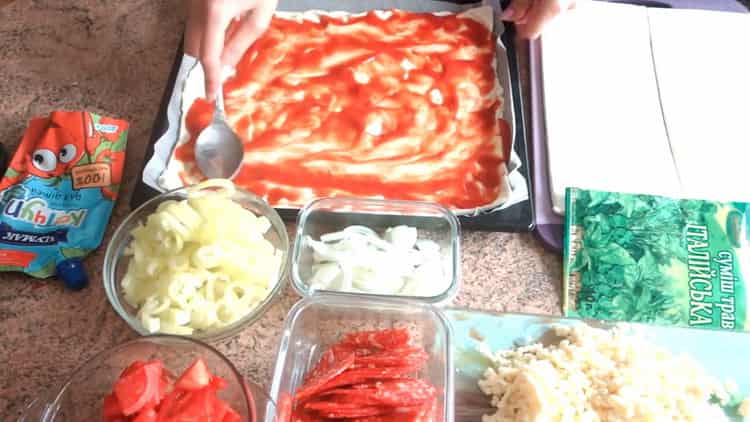 To make puff pastry pizza in the oven, grease the dough with tomato