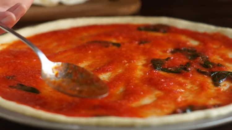 To make pizza margarita, grease the dough with sauce