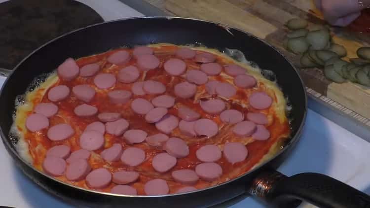 To make pizza in a pan, put sausage on the sauce