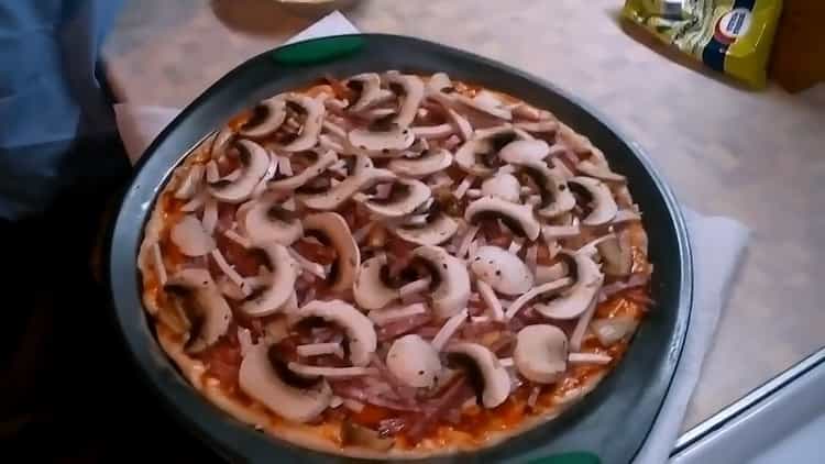 Hak de champignons om pizza met champignons en kaas te maken.