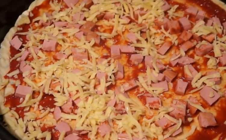 Pour faire une pizza avec des saucisses et du fromage, mettez la garniture sur la pâte