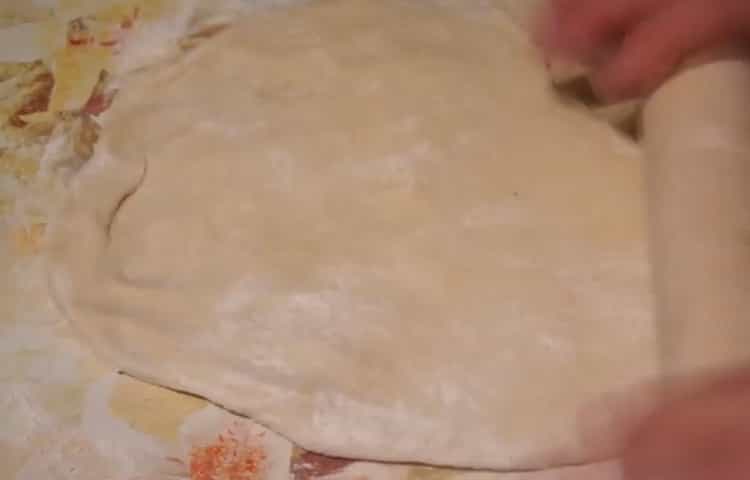 To make pizza with sausage and cheese, roll out the dough