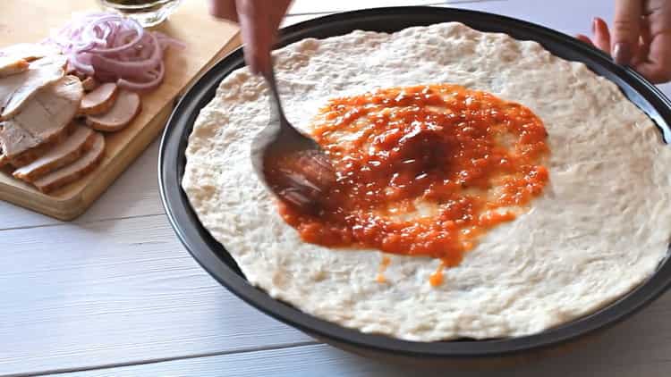 Para hacer pizza con pollo, engrase la forma con salsa