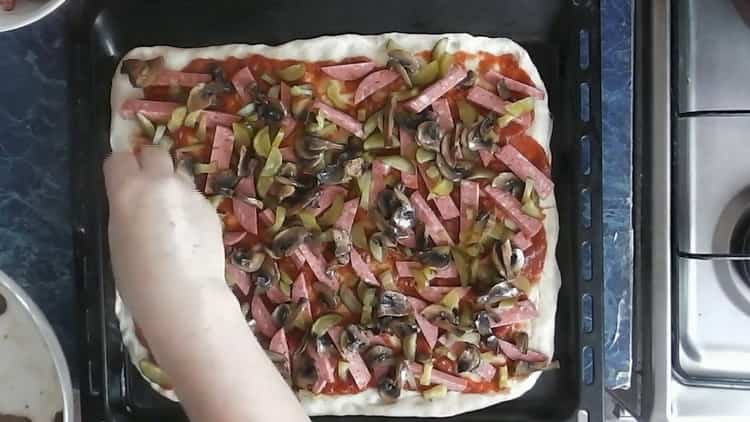 Para hacer pizza con pepinillos, ponga los champiñones sobre la masa.