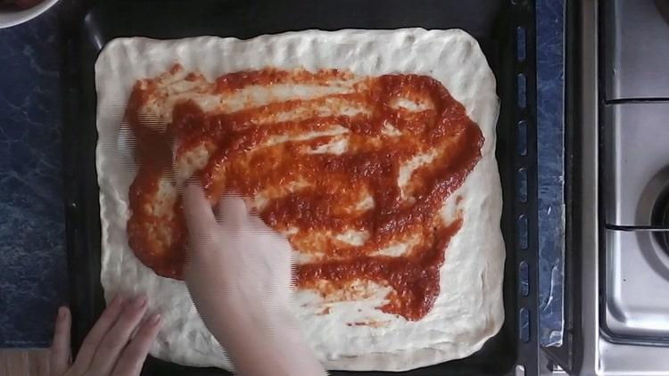Da biste napravili pizzu s krastavcima, namažite tijesto kečapom