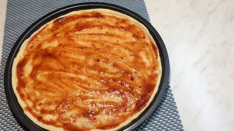 Pour la pizza César, graisser la pâte avec de la sauce