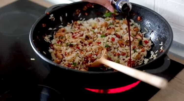 Ajouter la sauce soja pour cuisiner le riz avec les légumes et le poulet