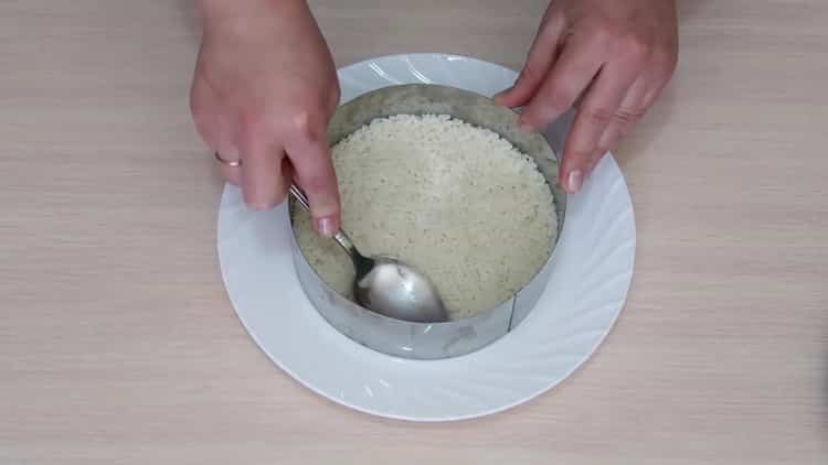 Para preparar una ensalada con aguacate y salmón, ponga el arroz en un molde.