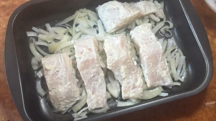 Selon la recette de cuisson de la sandre au four, mettez l'oignon et le poisson sur une plaque à pâtisserie