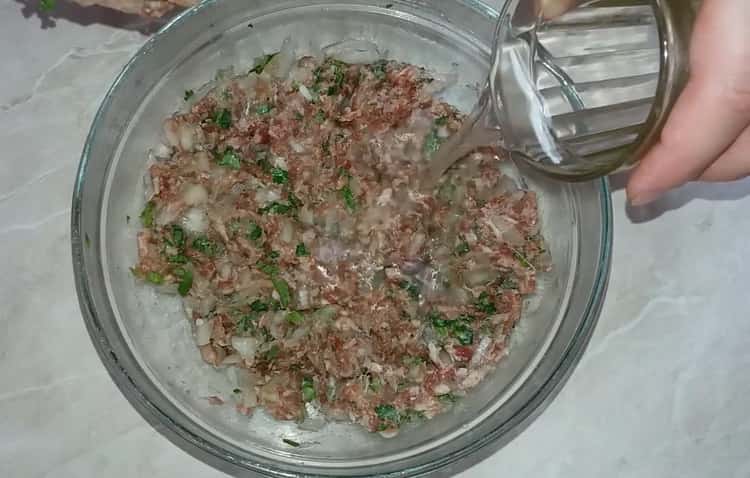Para preparar khinkali de acuerdo con una receta simple con una foto, agregue agua a la carne picada
