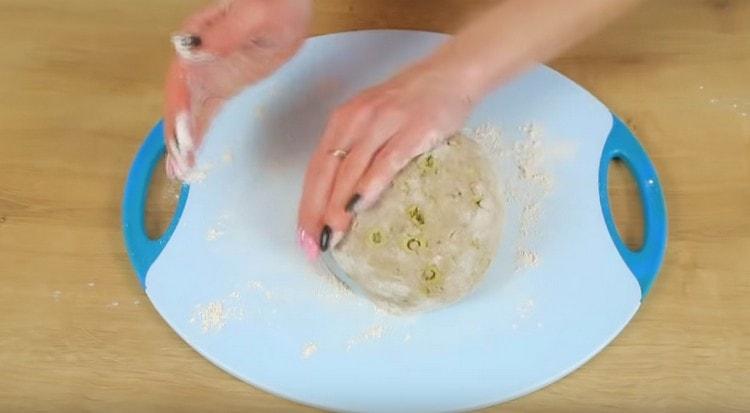 Nous déplaçons la pâte sur une planche saupoudrée de farine et écrasons légèrement.