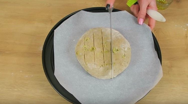 Having formed round bread, put it on a baking sheet covered with parchment and make shallow cuts on the loaf with a knife.