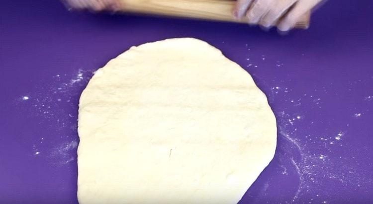 We roll out a piece of dough with a rolling pin.