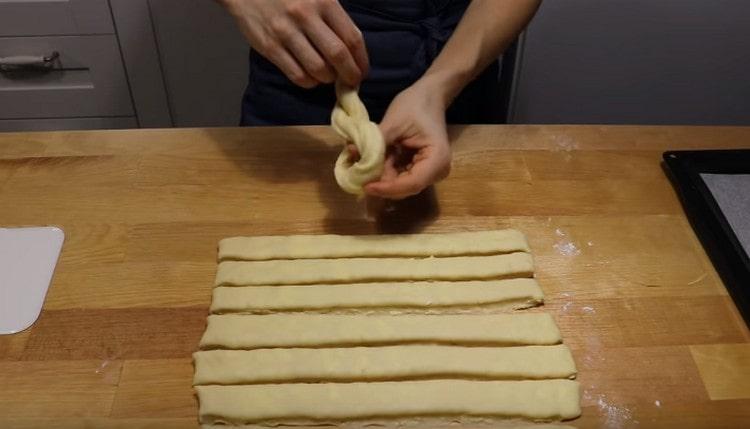 A flagella of dough folded in half is knotted.