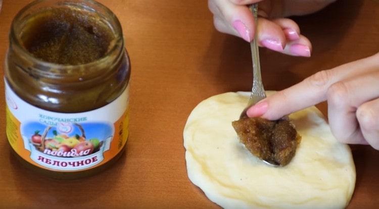 Amasar las bolas de masa en pasteles y extender la mermelada en el centro de cada uno de ellos.